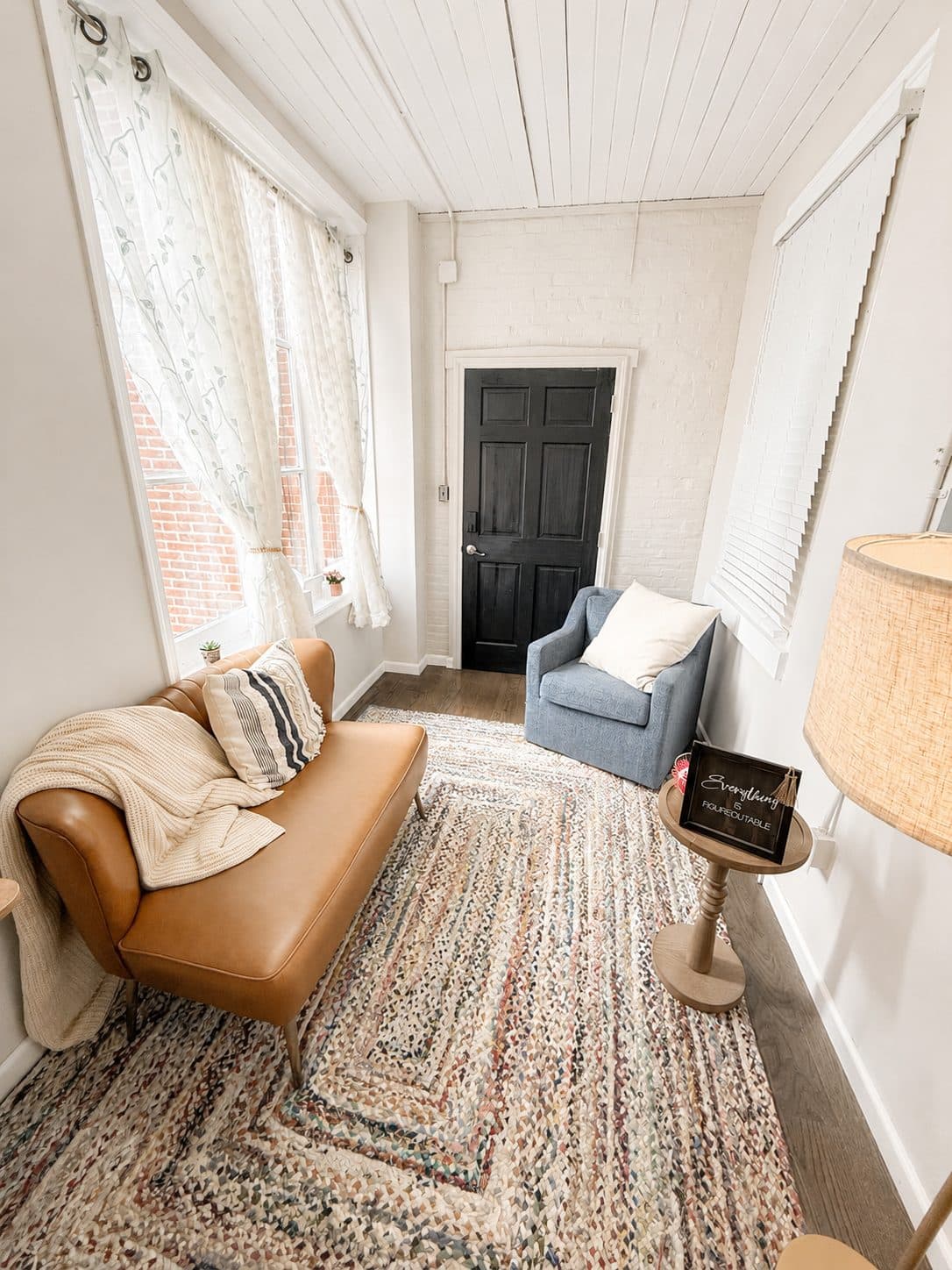 A quiet corner of the studio with a leather sofa, lace curtains, and soft natural light.